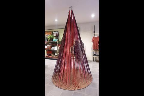 The shop creates atmosphere through the use of art and installations, including a cone made out of threads near the entrance